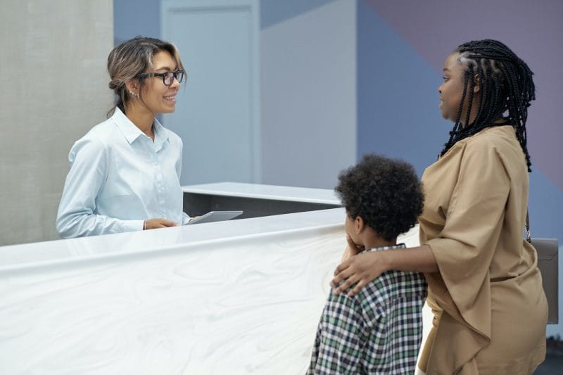 Friendly receptionist consulting young African woman with son