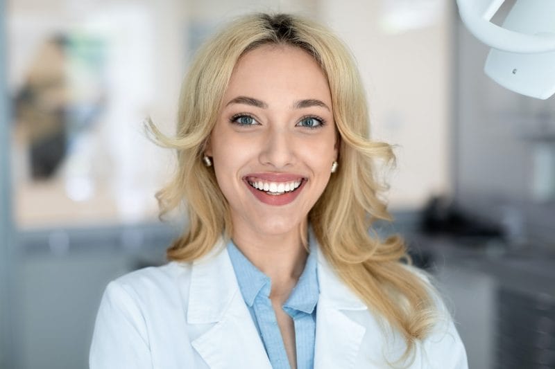 Beautiful woman dentist smiling in dental cabinet